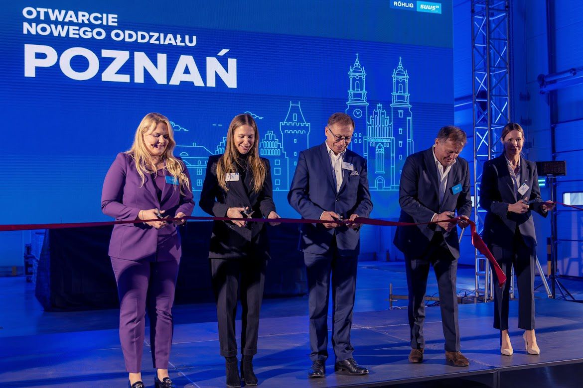 The photo shows representatives of SUUS Logistics, the mayor of Tarnów Podgórny and Head of the Investor Relations Department, Katja Lożina, during the grand opening of the company's warehouse. Individuals cut the red sash with scissors. - grafika artykułu