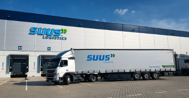 The photo shows the warehouse of SUUS Logistics. A TIR is standing in front of it.