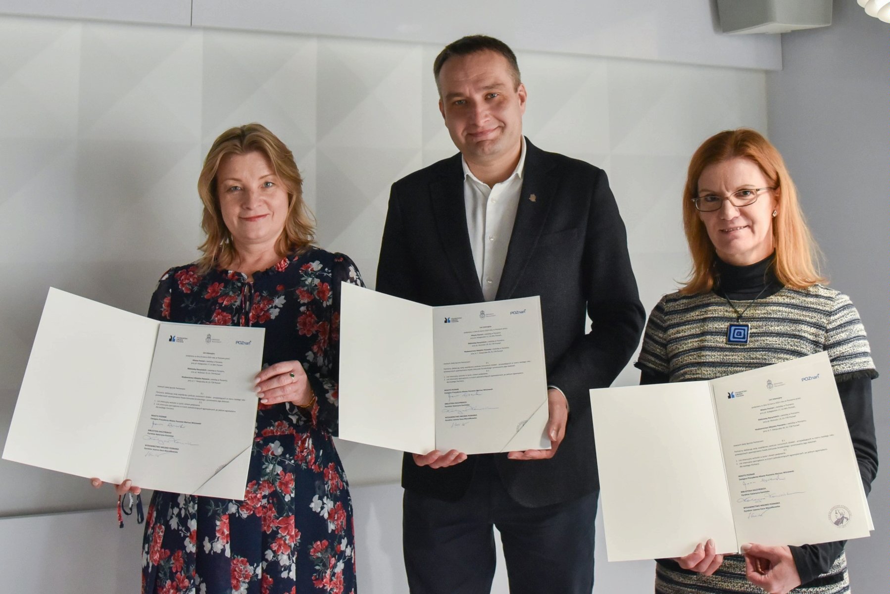 Photo shows three people holding open folders with the signed letter of intend - grafika artykułu