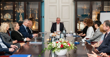 Na zdjeciu grupa ludzi za stołem, u szczytu stołu siedzi prezydent Poznania